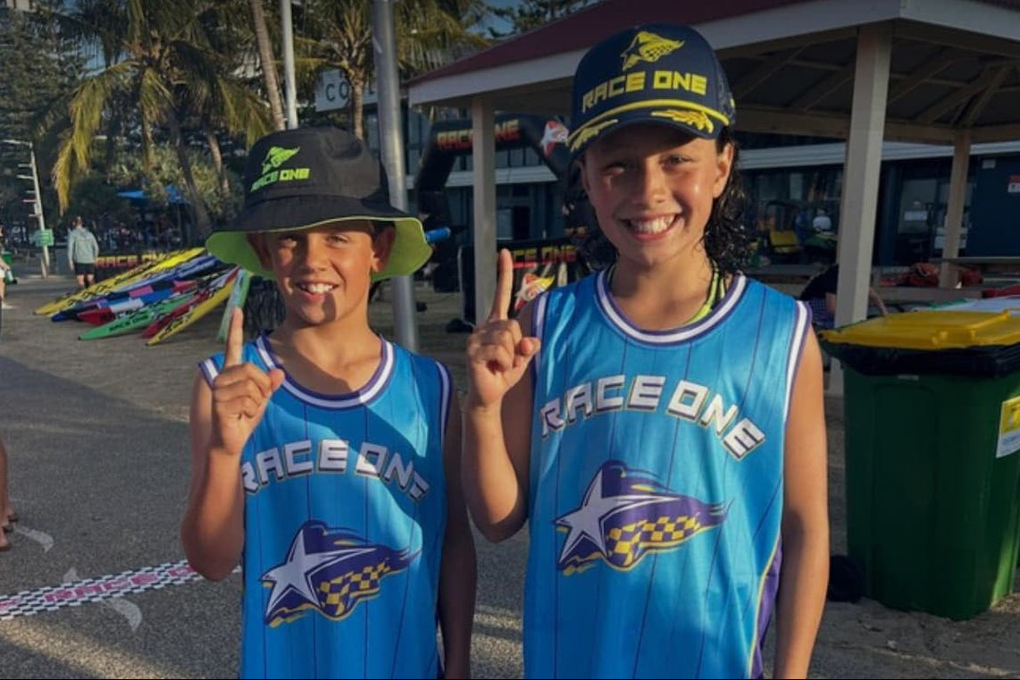 Two children in Race One branded jerseys and hats with Christmas lights above, promoting Christmas bundles.